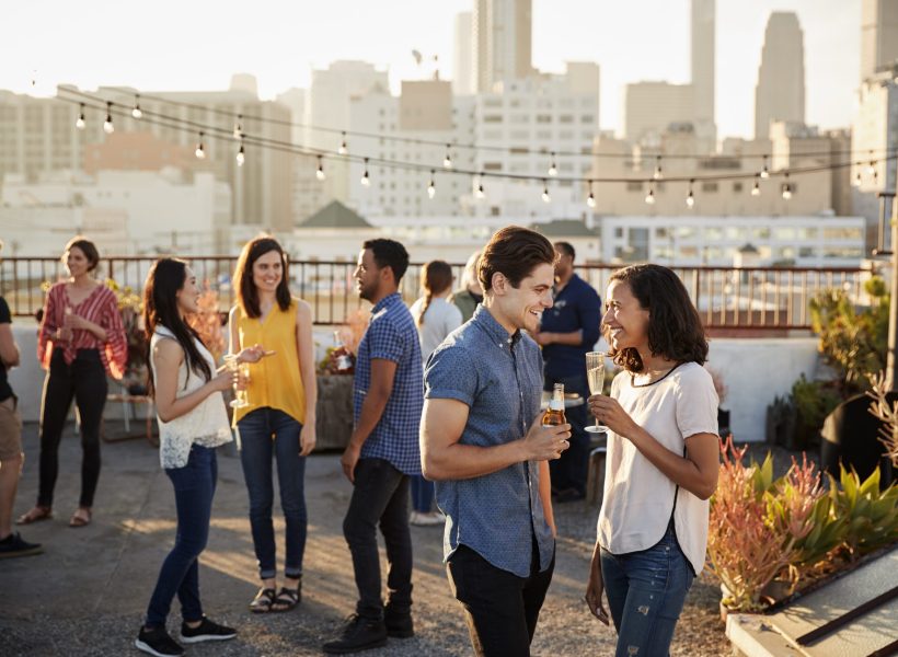 Friends Gathered On Rooftop Terrace For Party With City Skyline In Background